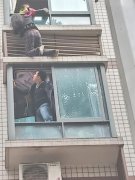 女子身体悬挂在窗外 楼下男子翻窗施救
