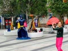 大妈身旁跳扇子舞  “蝙蝠侠”拎袋似举重